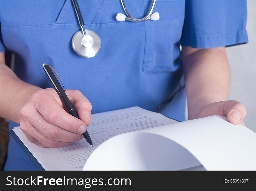 Hand of doctor with pen writing on prescription blank