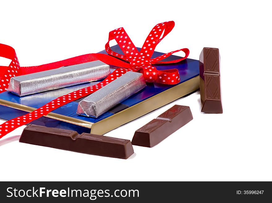 Blue box with chocolate slices wrapped in foil and decorated with a red ribbon. Presents on a white background. Blue box with chocolate slices wrapped in foil and decorated with a red ribbon. Presents on a white background.