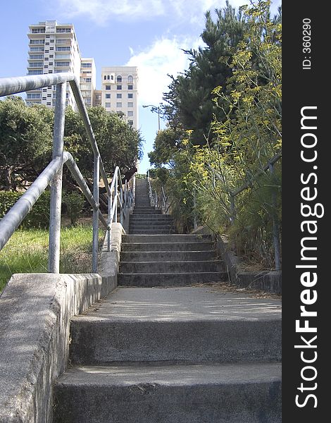 A long stairway leading up a hill to a group of city apartments. A long stairway leading up a hill to a group of city apartments.