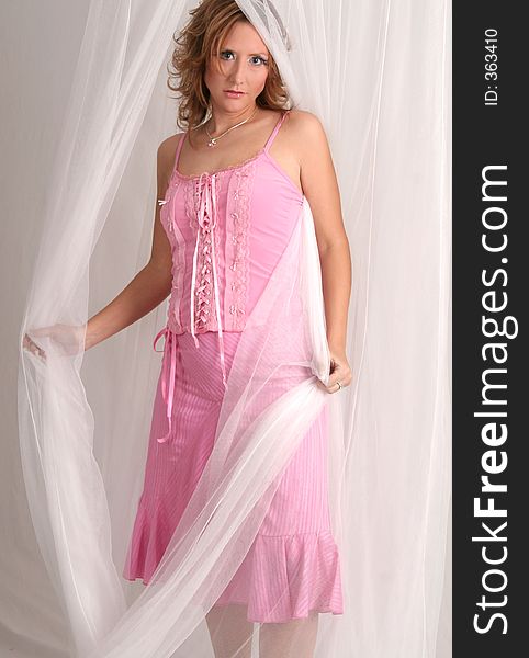 Woman in pink dress posing with white netting. Woman in pink dress posing with white netting