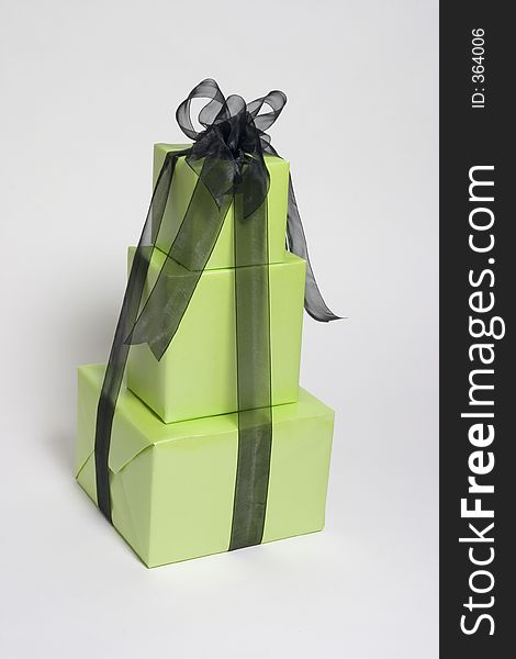 3 green wrapped presents stacked and wrapped in black ribbon. 3 green wrapped presents stacked and wrapped in black ribbon