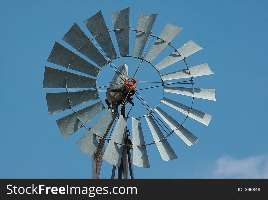 An old windmill sits idle against a blue sky full of wispy clouds.