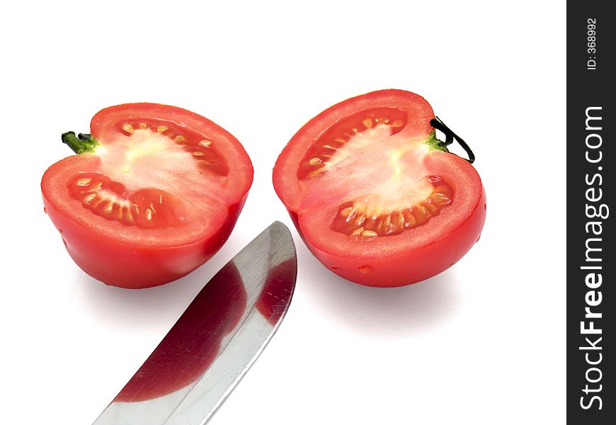 Two half of tomato with knife over the white. Two half of tomato with knife over the white