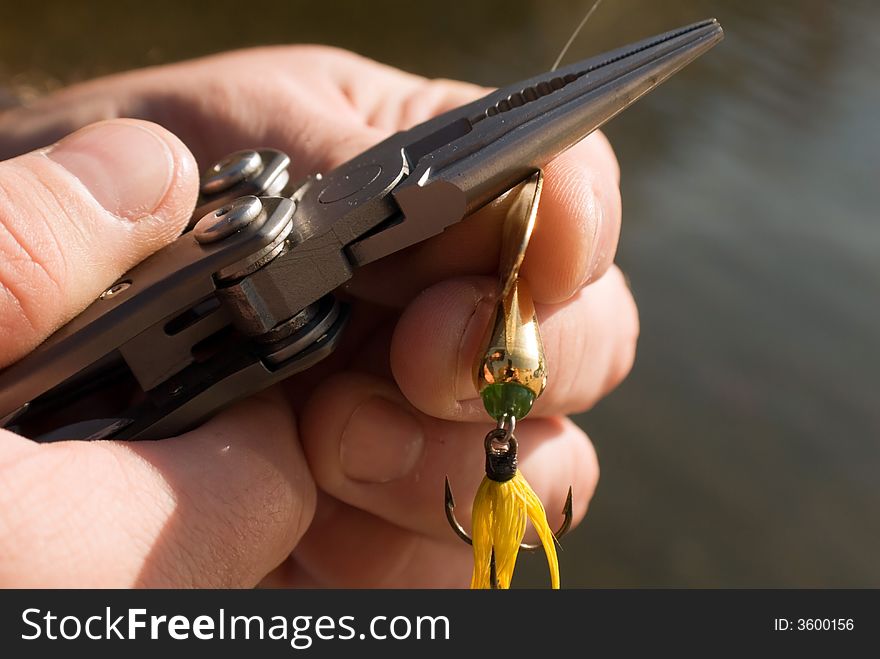 Man holding a lure and getting it attached to the line. Man holding a lure and getting it attached to the line.