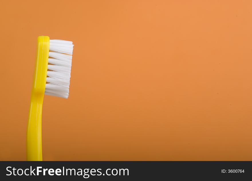Yellow toothbrush on an orange background.