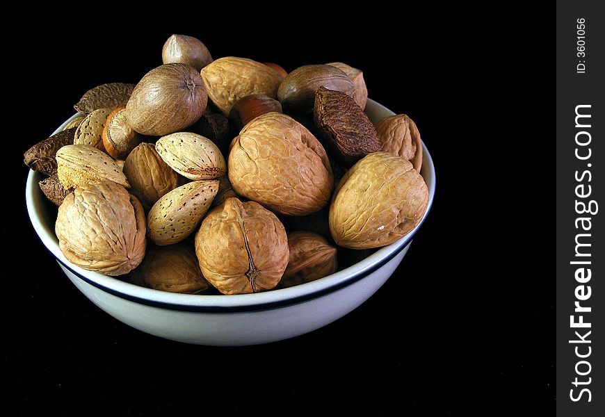 A bowl of mixed nuts against a black background. A bowl of mixed nuts against a black background.
