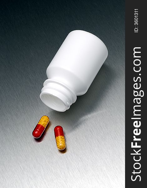 Bottle of pills with two pills on the surface. Bottle of pills with two pills on the surface