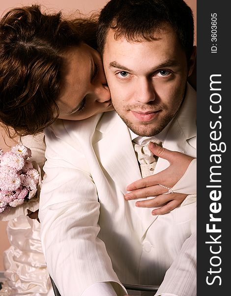 Young couple kissing in wedding wear with bouquet of chrysanthemum. Special pink toned photo f/x