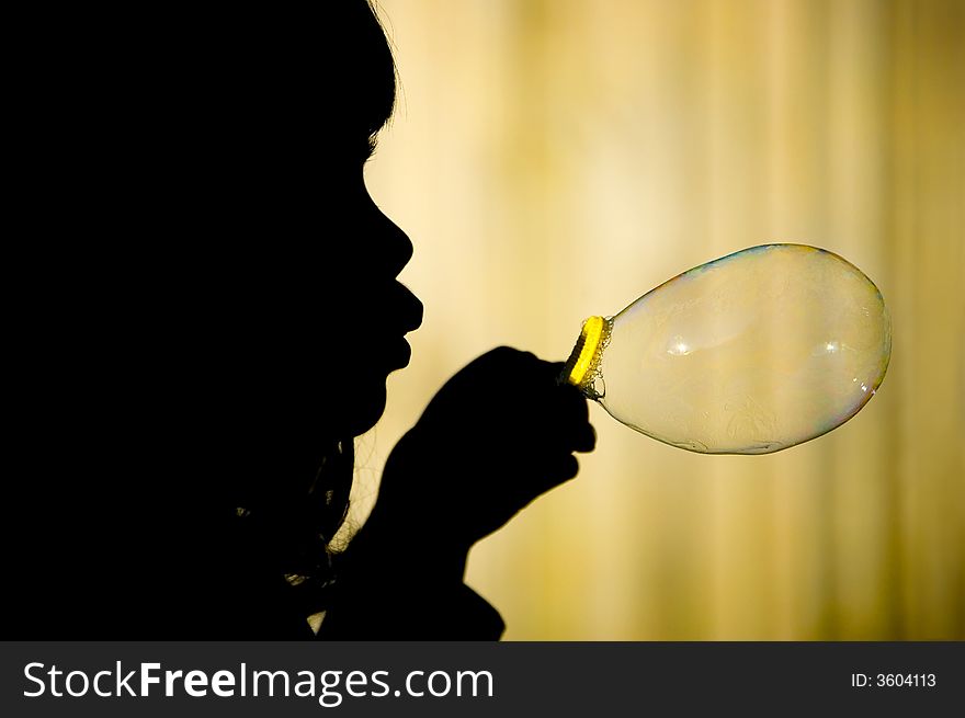 Silhouette of a little girl making a big bubble against yellow background. Silhouette of a little girl making a big bubble against yellow background.