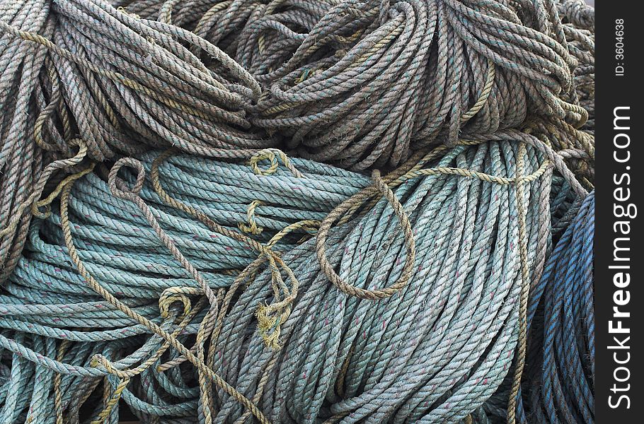 A collection of faded ropes coiled and stored on the quayside of a fishing port. A collection of faded ropes coiled and stored on the quayside of a fishing port.