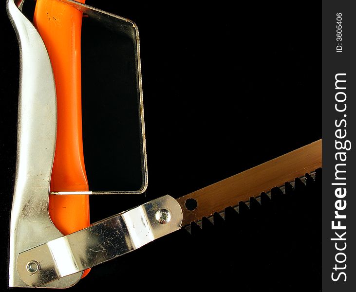 An orange hacksaw against a black background. An orange hacksaw against a black background.