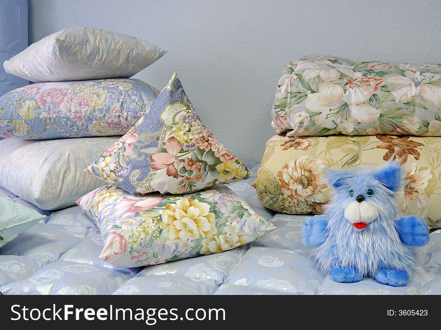 Stacks of floral pillows and a stuffed animal on a bed. . Stacks of floral pillows and a stuffed animal on a bed.