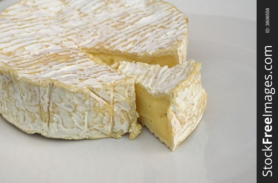 A ripe camembert cheese with a slice cut out.