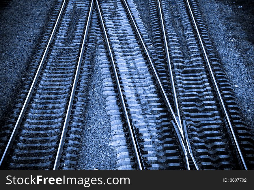 Three crossing railway tracks in cold blue tones