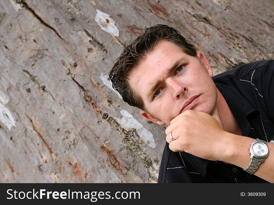 Young Male Model sitting against a tree in the park. Young Male Model sitting against a tree in the park