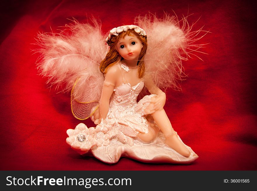 Portrait of a handmade angel figurine on a stylish red background.