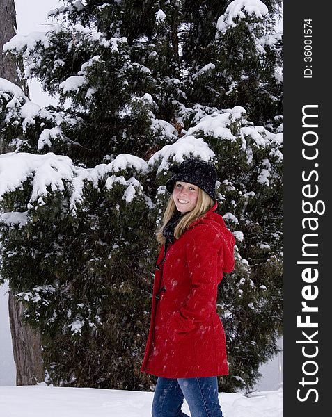 Blonde female in red coat and black hat in the middle of a snow storm. Blonde female in red coat and black hat in the middle of a snow storm.