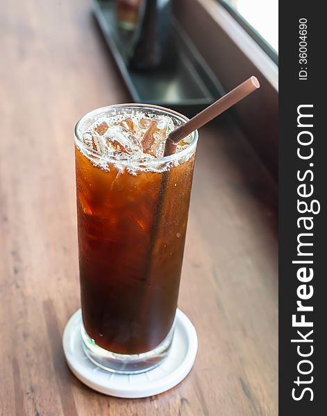 Iced black coffee on the wooden table in coffee cafe.
