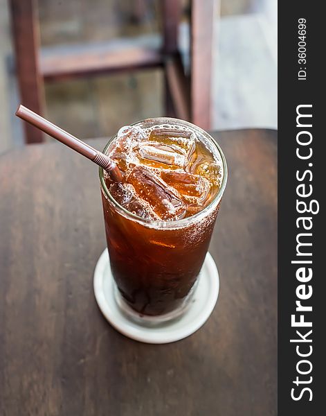 Iced black coffee on the wooden table in coffee cafe.