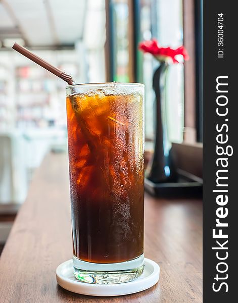 Iced black coffee on the wooden table in coffee cafe.