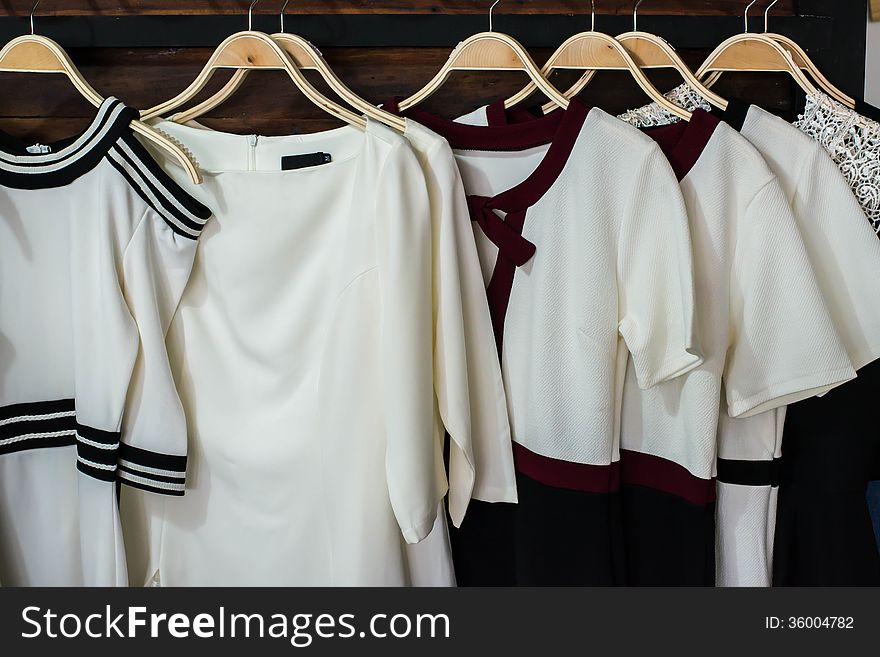 Many white blouses on hangers in the dressing room.