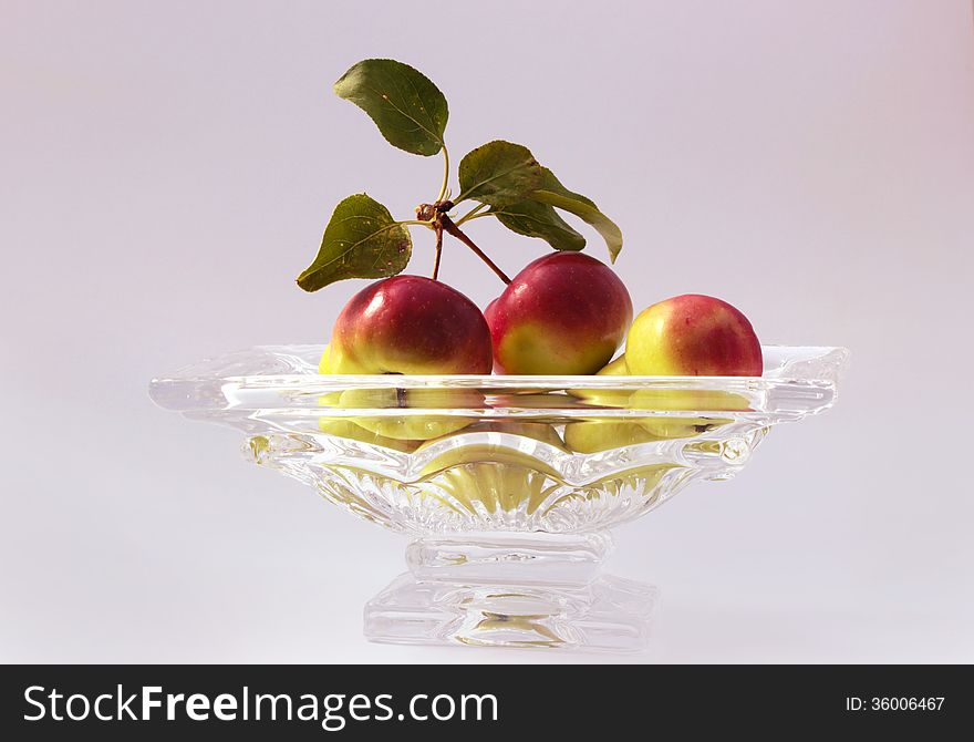 Crabapples in a glass bowl on a white background.