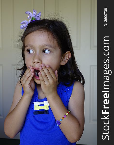 A young girl of Asian descent holds her hands to her mouth as she appears with a surprised look on her face. A young girl of Asian descent holds her hands to her mouth as she appears with a surprised look on her face.