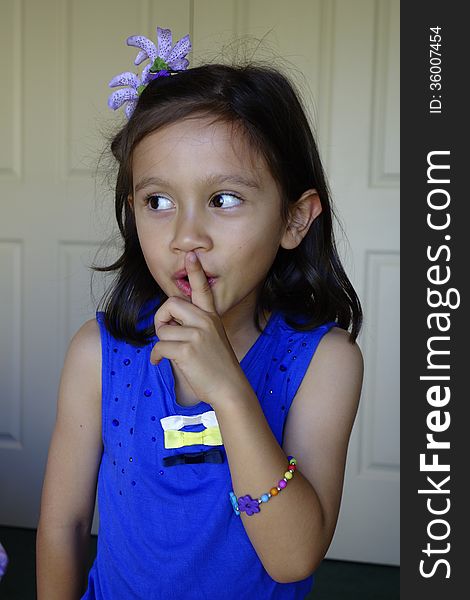 A young girl of asian descent holds her finger against her lips signalling silence. A young girl of asian descent holds her finger against her lips signalling silence.
