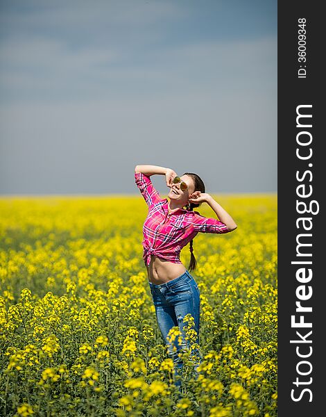 Young beautiful woman in flowering field in summer. Outdoors