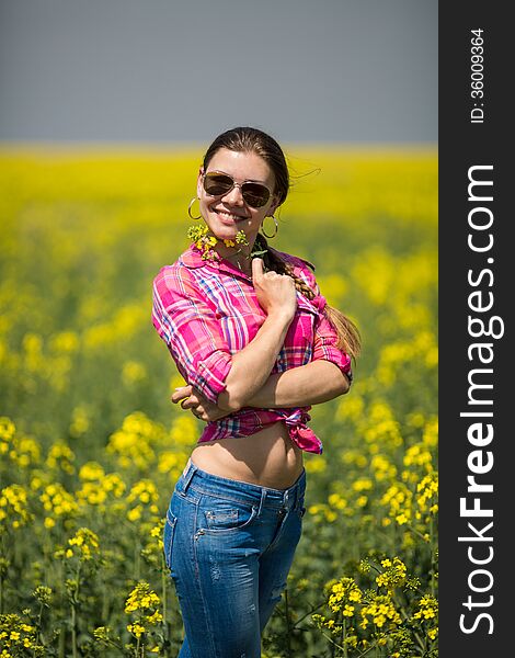 Young beautiful woman in flowering field in summer. Outdoors