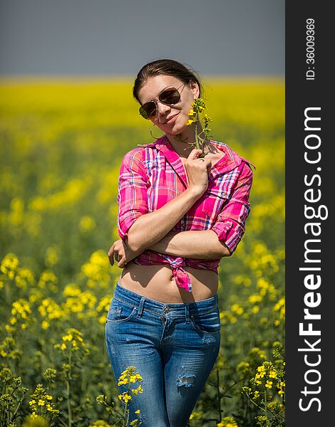 Young beautiful woman in flowering field in summer. Outdoors