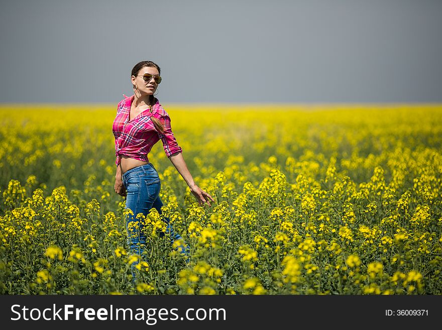 Young beautiful woman in flowering field in summer. Outdoors