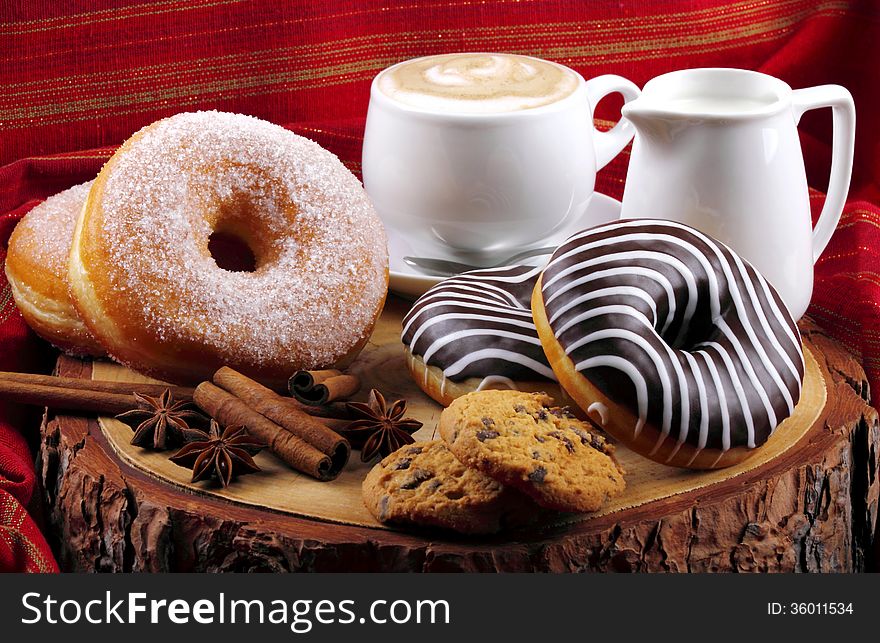 Donut with chocolate and sugar on wooden stump with cinnamon and background with red cloth. Donut with chocolate and sugar on wooden stump with cinnamon and background with red cloth