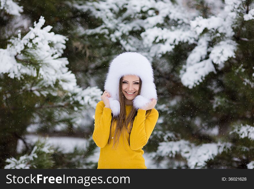 Winter portrait of beautiful smiling woman with snowflakes in white furs