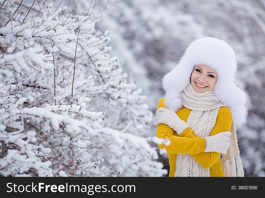 Winter portrait of beautiful smiling woman with snowflakes in white furs