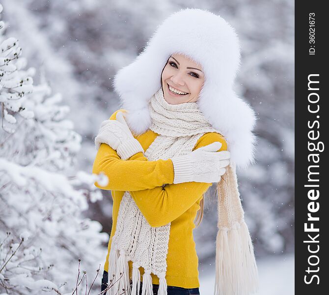 Winter portrait of beautiful smiling woman with snowflakes in white furs