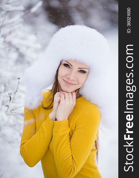 Winter portrait of beautiful smiling woman with snowflakes in white furs