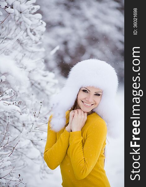 Winter portrait of beautiful smiling woman with snowflakes in white furs