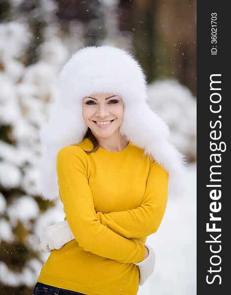 Winter portrait of beautiful smiling woman with snowflakes in white furs