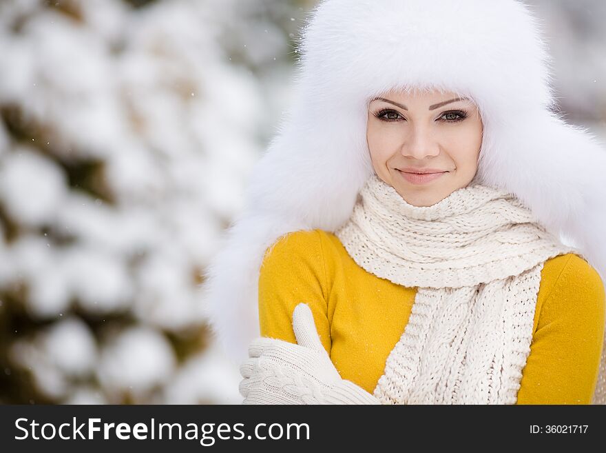 Winter portrait of beautiful smiling woman with snowflakes in white furs