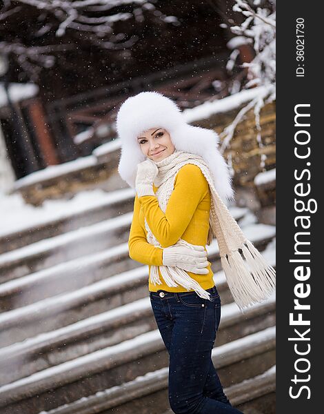 Winter portrait of beautiful smiling woman with snowflakes in white furs