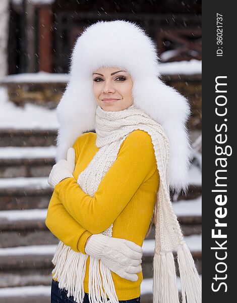 Winter portrait of beautiful smiling woman with snowflakes in white furs