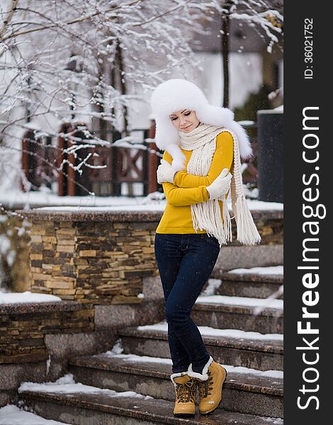 Winter portrait of beautiful smiling woman with snowflakes in white furs