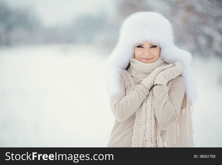 Winter portrait of beautiful smiling woman with snowflakes in white furs