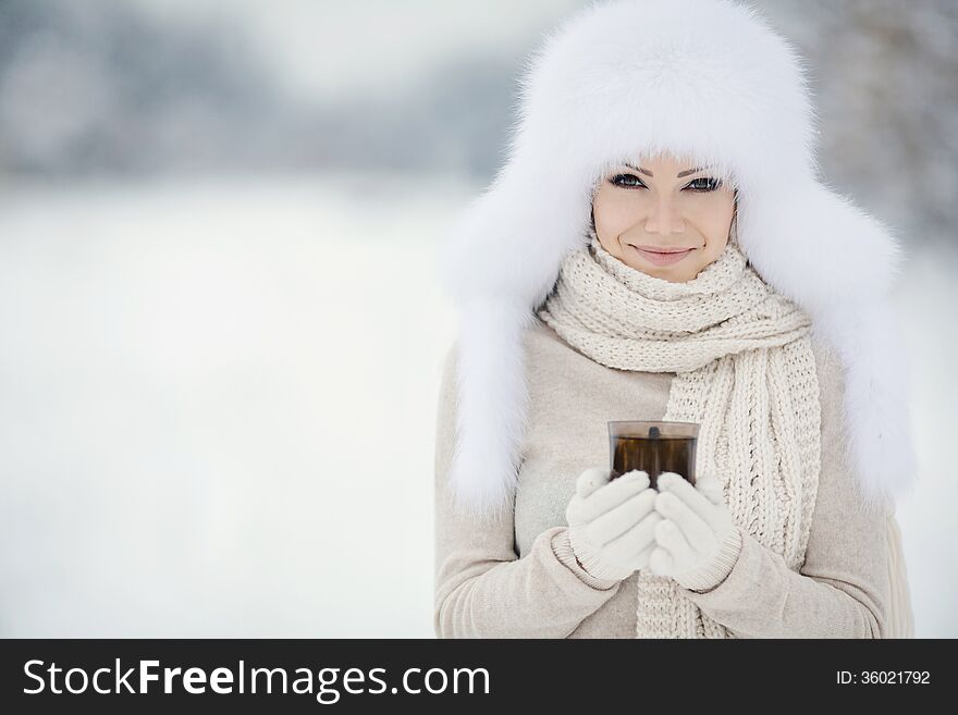 Winter portrait of beautiful smiling woman with snowflakes in white furs