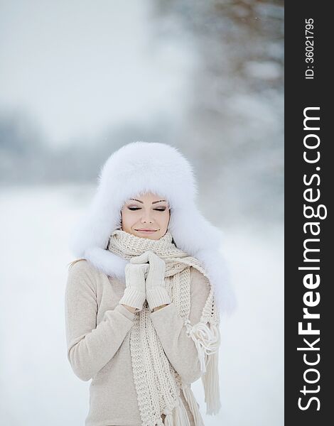 Winter portrait of beautiful smiling woman with snowflakes in white furs