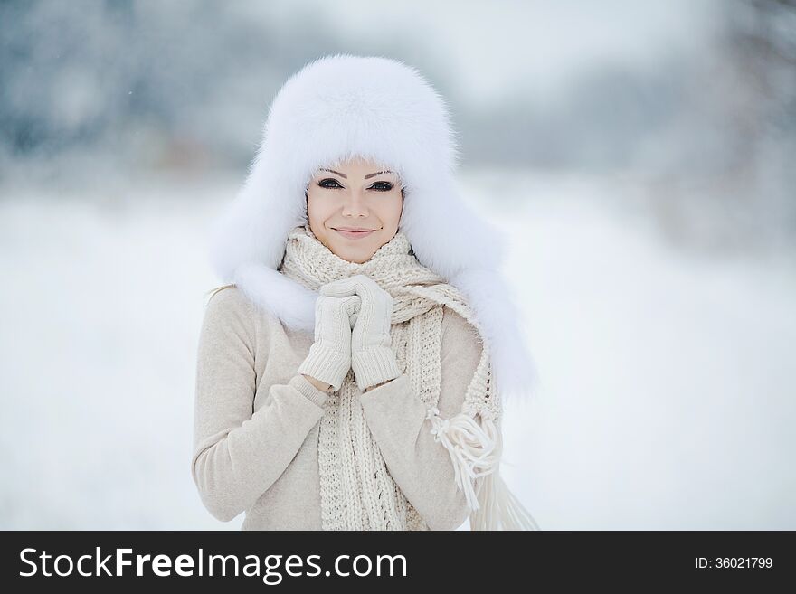 Winter portrait of beautiful smiling woman with snowflakes in white furs