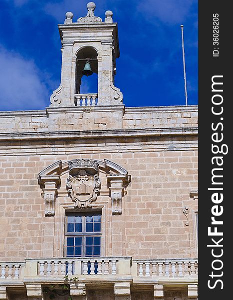 The bell tower of the Selmun palace. Also visible is the long balcony on the facade of the Palace. On the facade an old sculpture can also be seen. The bell tower of the Selmun palace. Also visible is the long balcony on the facade of the Palace. On the facade an old sculpture can also be seen.