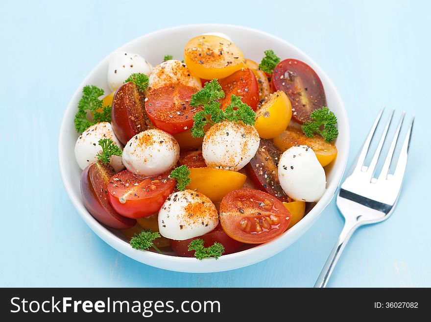 Bowl of salad with mozzarella, herbs and colorful cherry tomatoes, top view, horizontal