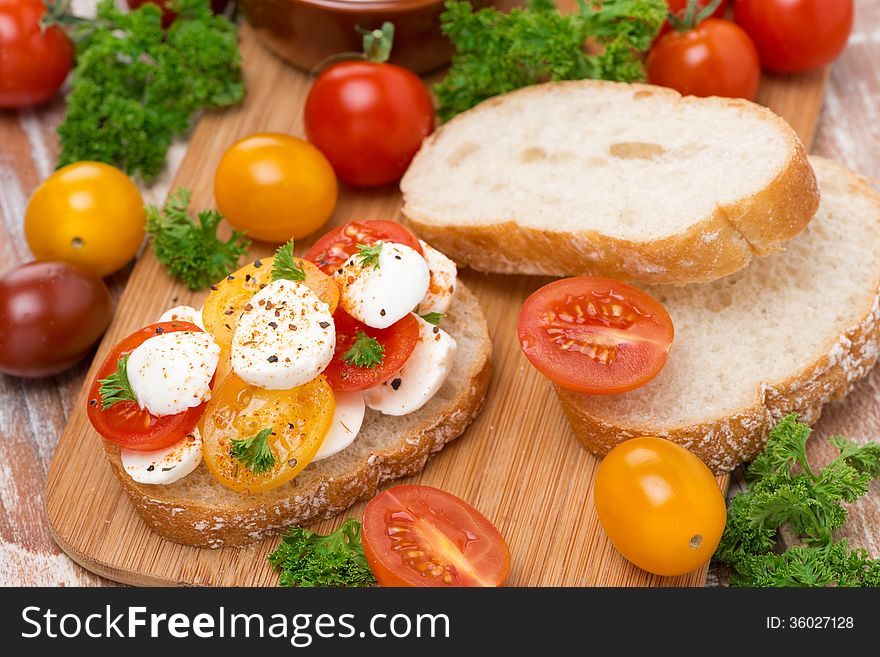 Ciabatta with mozzarella and colorful cherry tomatoes on a wooden board, top view, horizontal